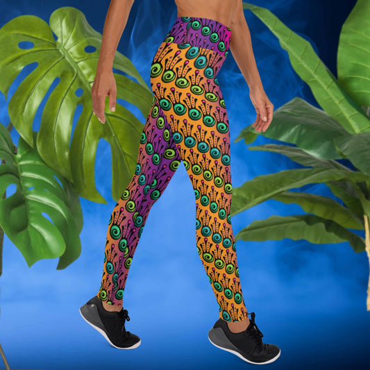 Woman from the waist down wearing high-waist Tribal Frog funky festival yoga leggings standing facing to the right with her hands by her sides and her right leg forward. The woman is standing in front of a smoky blue background in front of two large leafy plants. The fire tribal frog pattern is an abstract pattern with a blended purple, pink and orange background.