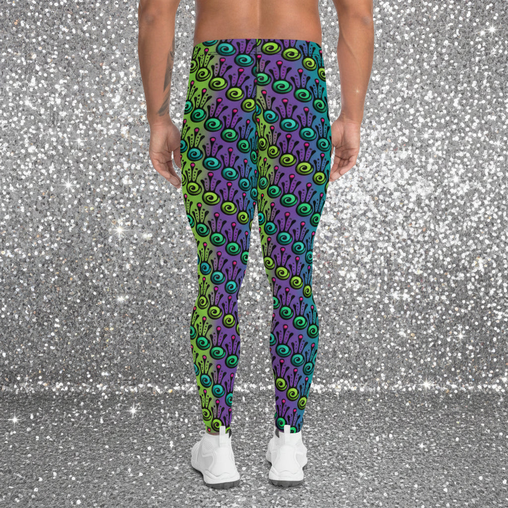 Man from the waist down wearing men's jungle tribal frog funky festival yoga leggings standing facing away with his hands by his sides. He is wearing white trainers and is standing on a nightclub dance floor with other people in the background and surrounded by green, purple and pink lighting. The jungle tribal frog pattern is an abstract pattern with a blended green and purple background.