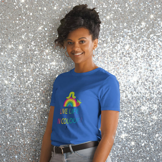 Woman wearing a royal blue 100% cotton vibrant, rainbow live life in colour t-shirt in a bohemian interior decorated with plants.
