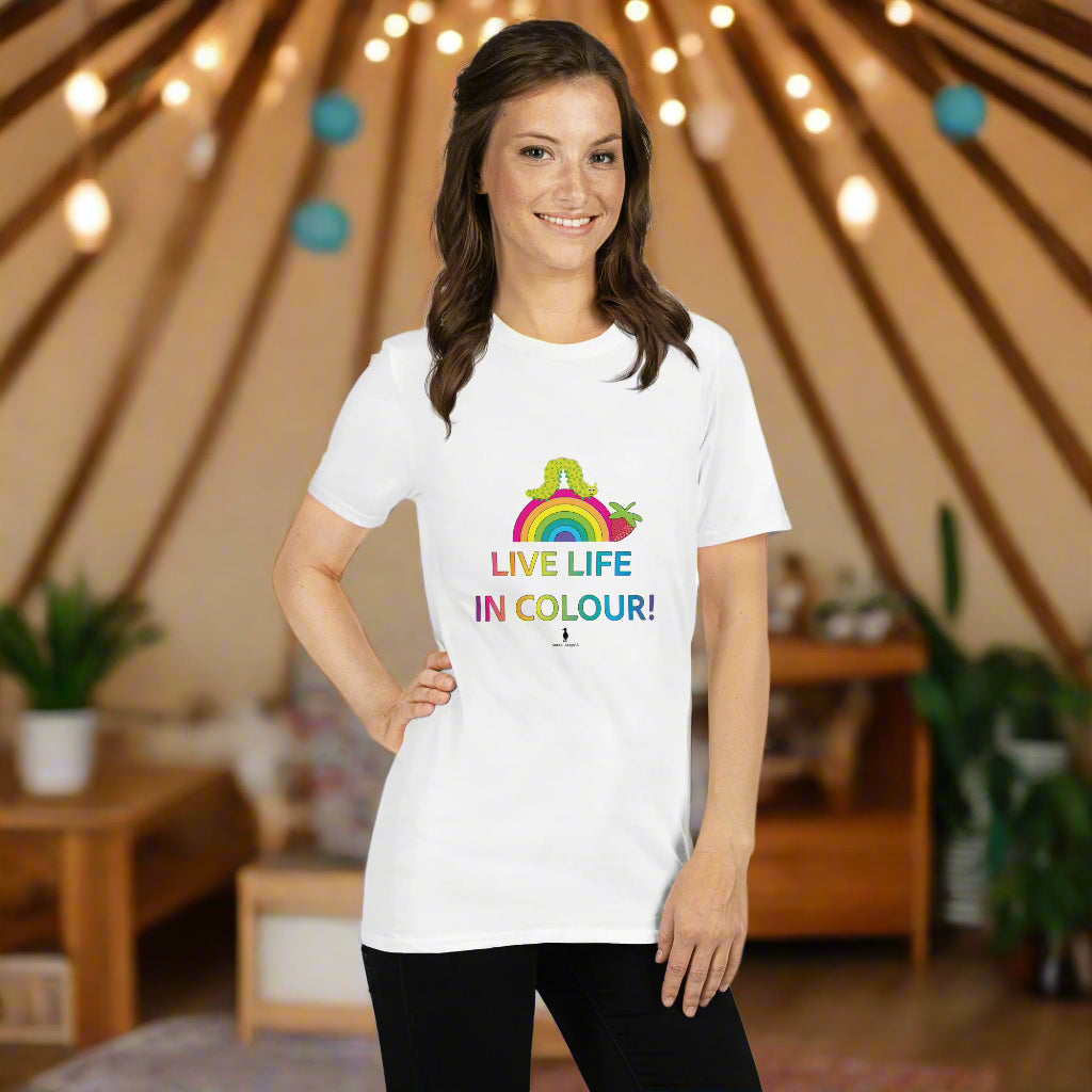 Woman wearing a white 100% cotton vibrant, rainbow live life in colour t-shirt in a bohemian yurt interior decorated with fairy lights, rugs, candles and plants.