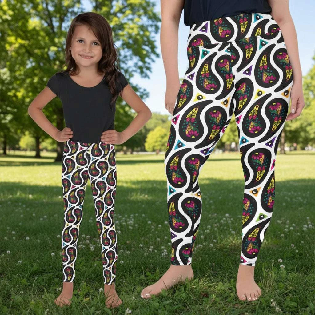 Woman and child wearing matching festival leggings designed in Wales - bold White Paisley Party pattern. Silver sequin background | Sassy Seagull
