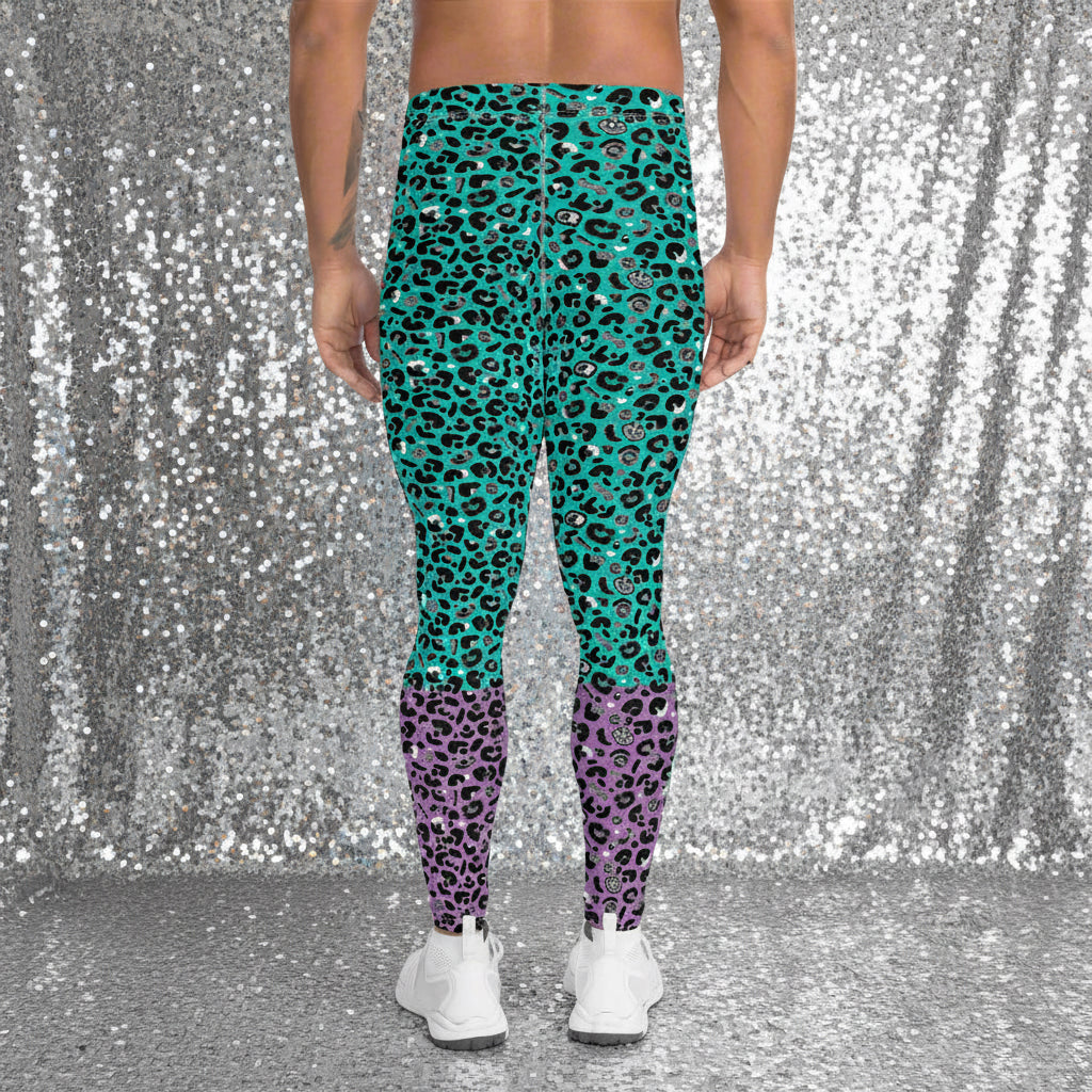 Man from the waist down wearing mens Purple and Green Leopard Glamour funky festival yoga leggings standing facing away with his hands by his sides. The man is standing in a park in spring with pink and yellow tulips flowering and trees in the background. This design features an animal print pattern in black, grey and white, printed at a medium scale. The top 3/4 background is mint green with the bottom 1/4 purple