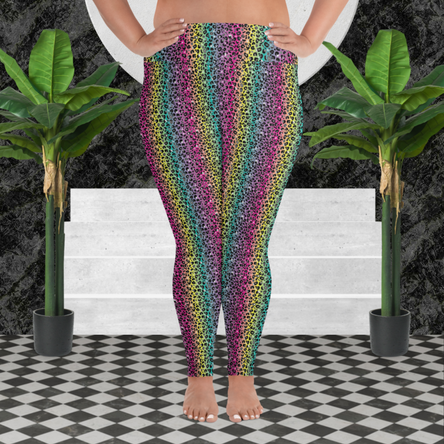 A curvy woman from the waist down wearing plus-size high-waist Rainbow Leopard Glamour funky festival yoga leggings standing facing forwards with her hands on her hips. The woman is standing on a black and white tiled floor in front of some white steps and a black and grey marble background. There is a leafy plant on the floor at each side of the steps. The rainbow leopard glamour design is an animal print pattern in black, grey and white, printed at a small scale against a blended rainbow background