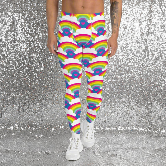 Man from the waist down wearing men's Rainbow Love funky festival yoga leggings standing facing forwards with his hands by his sides. The man is standing on a colour splashed dance floor with colourful light streams criss crossing behind him in reds, yellows, greens and blues. The rainbow love pattern features repeating rainbows and white fluffy clouds with a small pink heart beneath each rainbow. The background colour is royal sky blue