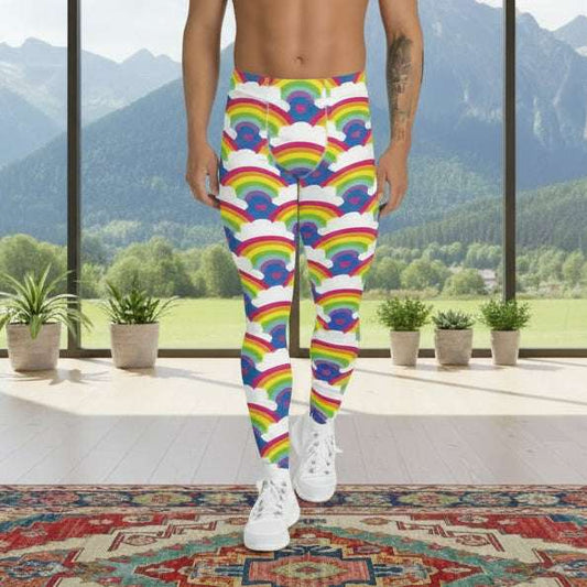 Man from the waist down wearing men's Rainbow Love funky festival yoga leggings standing facing forwards with his hands by his sides. The man is standing on a colour splashed dance floor with colourful light streams criss crossing behind him in reds, yellows, greens and blues. The rainbow love pattern features repeating rainbows and white fluffy clouds with a small pink heart beneath each rainbow. The background colour is royal sky blue
