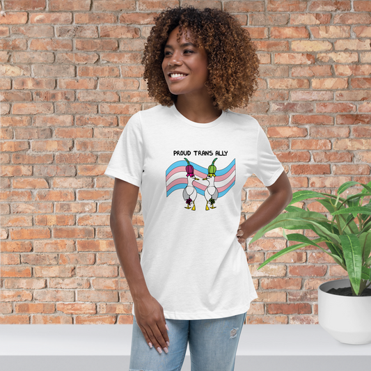 Woman standing facing forwards and looking to the left, wearing a fitted white Sassy Seagull Proud Trans Ally LGBTQ+ Pride T-Shirt and pale stonewash blue jeans. She is standing in front of a brick wall with a plant on a white step behind her. The t-shirt is white with short sleeves. The graphic shows two cartoon style seagulls wearing colourful hats walking away in front of an trans pride flag, underneath the wording Proud Trans Ally. It is a soft playful design for everyday wear.