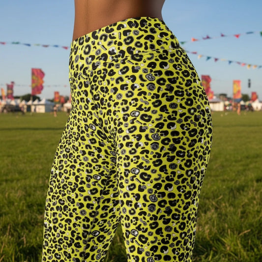 High waist Pink and Yellow Leopard Glamour festival yoga leggings close up side view against a rustic boho background with bunting, plants and fairy lights. The pink and yellow leopard glamour design is a bold animal printed pattern in black, grey and white against a bold yellow and pink background. Designed in Wales, UK | Sassy Seagull.