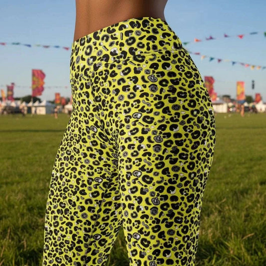 High waist Pink and Yellow Leopard Glamour festival yoga leggings close up side view against a rustic boho background with bunting, plants and fairy lights. The pink and yellow leopard glamour design is a bold animal printed pattern in black, grey and white against a bold yellow and pink background. Designed in Wales, UK | Sassy Seagull.
