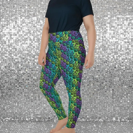 High waist Plus-Size Jungle Tribal Frog festival yoga leggings side view. Woman is standing in a boho interior room. The Tribal Frog design is a bold colourful abstract print on a blended green, purple and blue background. Designed in Wales, UK | Sassy Seagull.