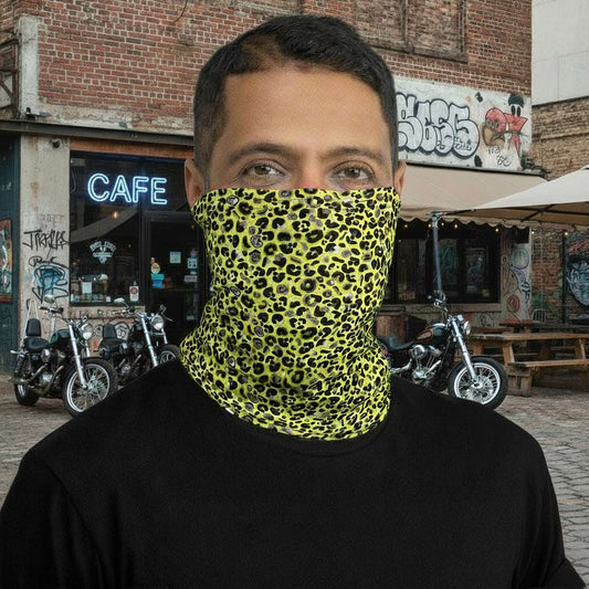 Man with short dark hair facing to the front wearing a black long sleeve top and a vibrant yellow and pink neck gaiter around his neck, covering his nose and mouth. In the background are some fairy lights and plants. This design features an animal print pattern in black, grey and white, printed at a medium scale. The top 3/4 background is bright yellow with the bottom 1/4 a hot pink colour. In this image the pink is not seen.