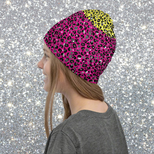 Girl with long dark blonde hair facing to the left wearing a grey top and a vibrant yellow and pink neck gaiter as a beanie hat. In the background are some fairy lights and plants. This design features an animal print pattern in black, grey and white, printed at a medium scale. The top 3/4 background is bright yellow with the bottom 1/4 a hot pink colour. In this image, the pink is the dominant colour
