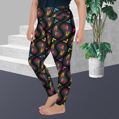A curvy woman from the waist down wearing high-waist Black Paisley Party funky festival yoga leggings standing facing to the left with her hands by her sides. The woman is standing on a grey floor in front of some white steps with a tall green plant to the right. The paisley party pattern  is a colourful repeating large paisley pattern, made up of vibrant colours including pink, orange, yellow, green, blue and purple. In between the paisley print are colourful triangles in the same colours
