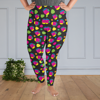 A curvy woman from the waist down wearing plus size high-waist Funk Party funky festival yoga leggings standing facing forwards with her hands on her hips. The woman is standing on a wooden floor with a white panelled wall in the background and a trailing plant on the floor. The funk party pattern  is an abstract pattern in vibrant pink, orange, yellow, green and blue in a spotty type arrangement on a black background
