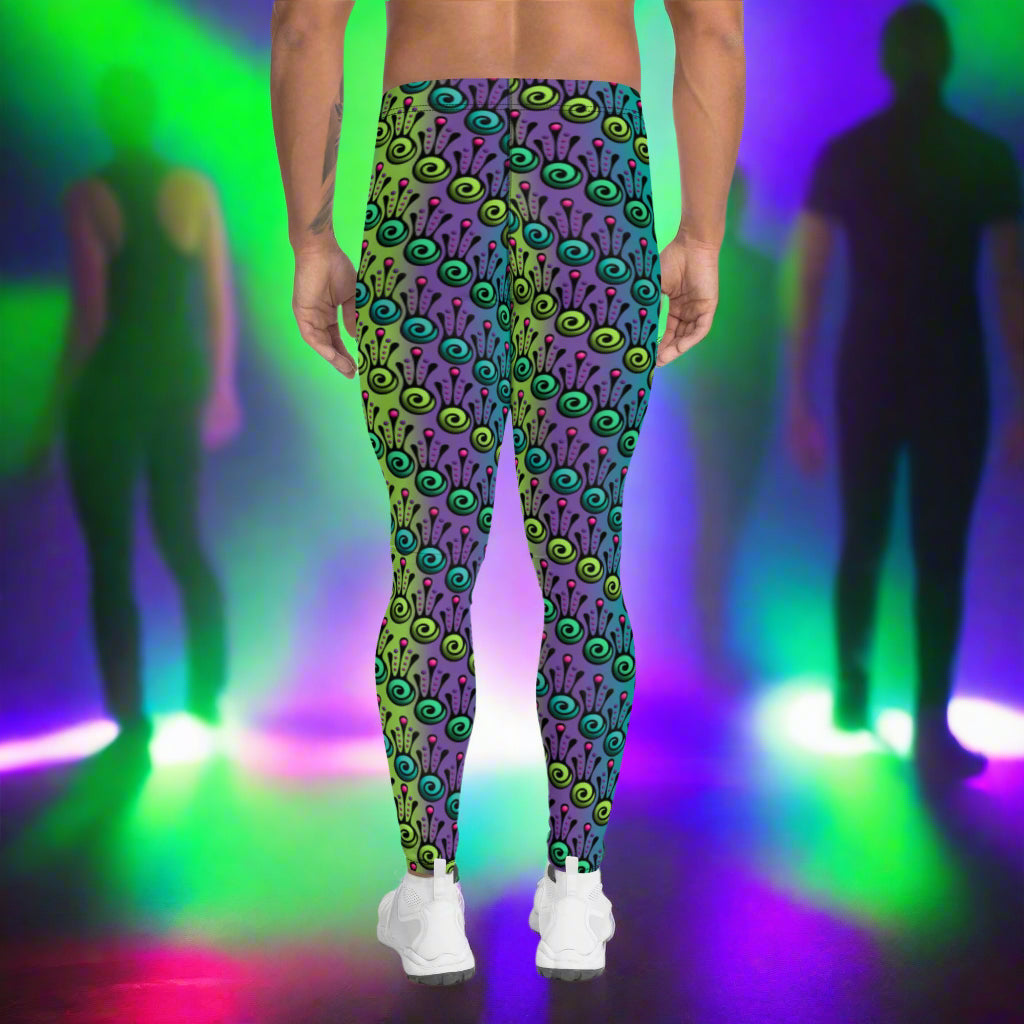 Man from the waist down wearing men's jungle tribal frog funky festival yoga leggings standing facing away with his hands by his sides. He is wearing white trainers and is standing on a nightclub dance floor with other people in the background and surrounded by green, purple and pink lighting. The jungle tribal frog pattern  is an abstract pattern with a blended green and purple background.