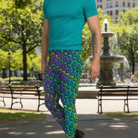 Man from the waist down wearing men's jungle tribal frog funky festival yoga leggings standing facing to the left with his hands by his sides. He is wearing white trainers and is standing on a nightclub dance floor with colourful green, pink and purple lights in the background. The jungle tribal frog pattern  is an abstract pattern with a blended green and purple background.