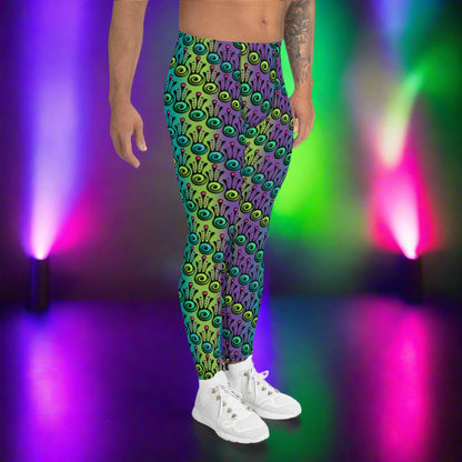Man from the waist down wearing men's jungle tribal frog funky festival yoga leggings standing facing to the right with his hands by his sides. He is wearing white trainers and is standing on a nightclub dance floor against a background of pink, purple and green stage lights. The jungle tribal frog pattern  is an abstract pattern with a blended green and purple background.