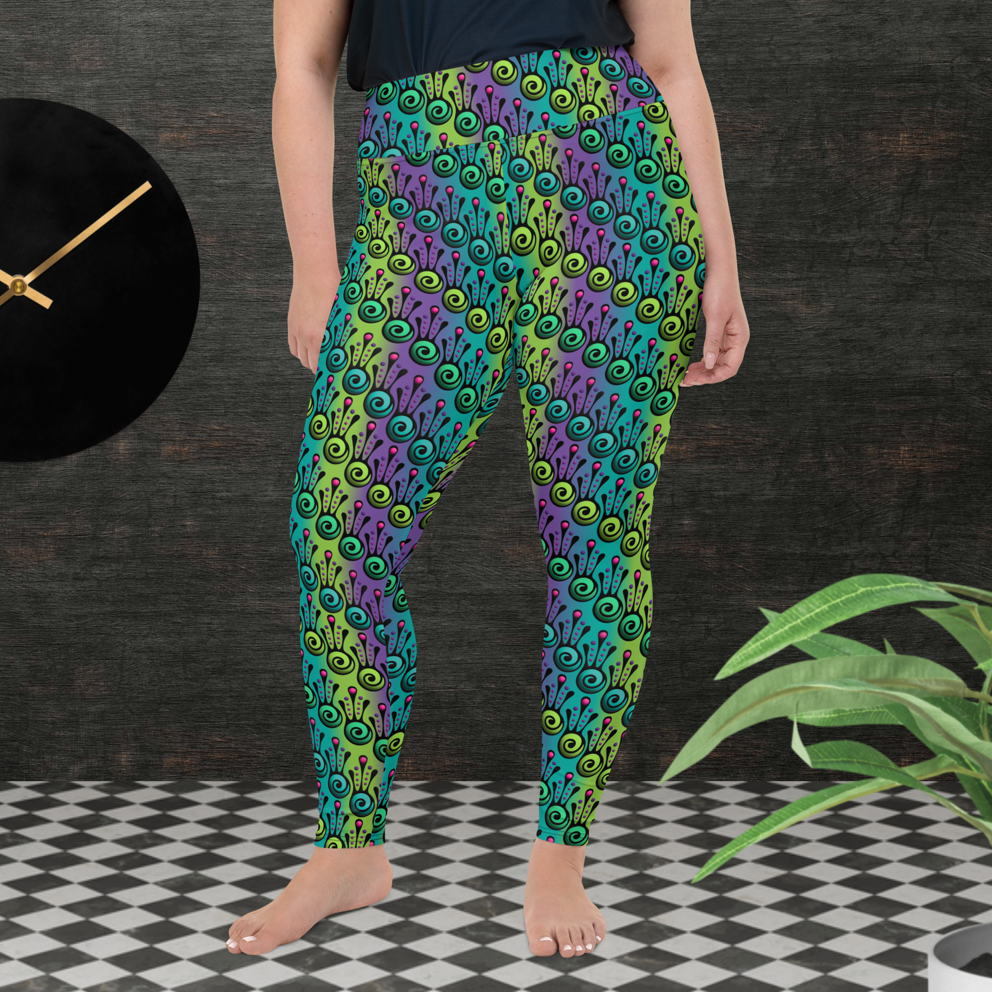 A curvy woman from the waist down wearing plus-size high-waist Tribal Frog funky festival yoga leggings standing facing forward with both hands by her sides. The woman is standing on a black and white tiled floor in front of a textured grey background with a black and gold wall clock to the left and a partially visible leafy plant on the floor in the bottom right. The jungle tribal frog pattern  is an abstract pattern with a blended green and purple background.