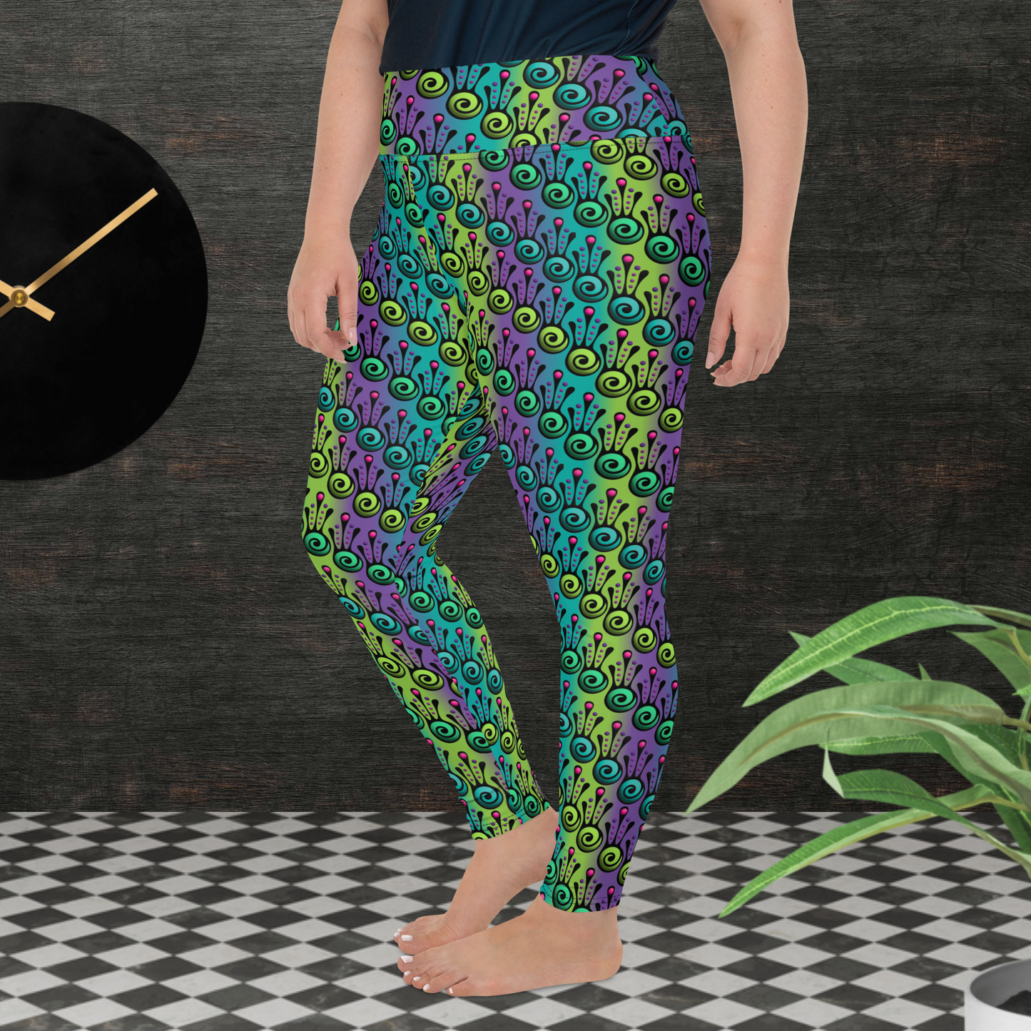 A curvy woman from the waist down wearing plus-size high-waist Tribal Frog funky festival yoga leggings standing facing to the left with both hands by her sides. The woman is standing on a black and white tiled floor in front of a textured grey background with a black and gold wall clock to the left and a partially visible leafy plant on the floor in the bottom right. The jungle tribal frog pattern  is an abstract pattern with a blended green and purple background.