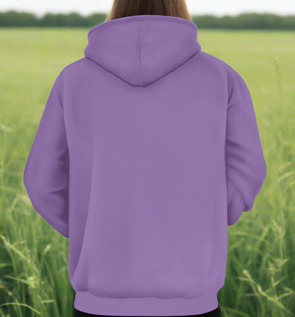 Person from the head down to the waist, posing standing facing away wearing a 100% cotton vibrant purple leopard leopard splodge graphic hoodie. They are standing against a backdrop of a grassy field. The hoodie is purple all over with no design on the back.
