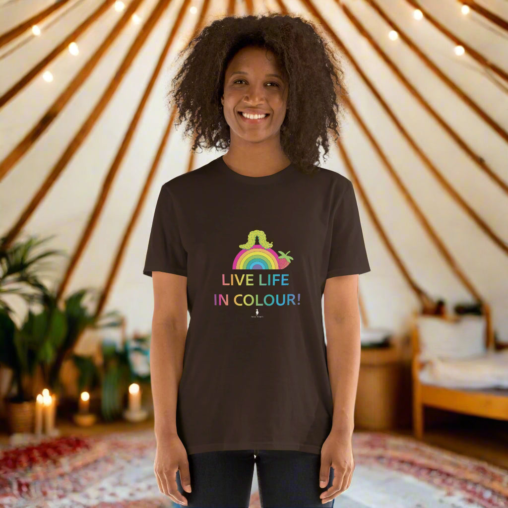 Woman wearing a chocolate brown 100% cotton vibrant, rainbow live life in colour t-shirt in a bohemian yurt interior decorated with fairy lights, rugs, candles and plants.