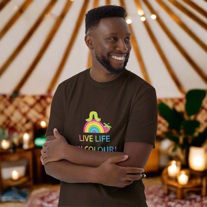 Man wearing a chocolate brown 100% cotton vibrant, rainbow live life in colour t-shirt in a bohemian yurt interior decorated with fairy lights, rugs, candles and plants.