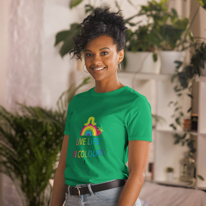 Woman wearing a green 100% cotton vibrant, rainbow live life in colour t-shirt in a bohemian interior decorated with plants.