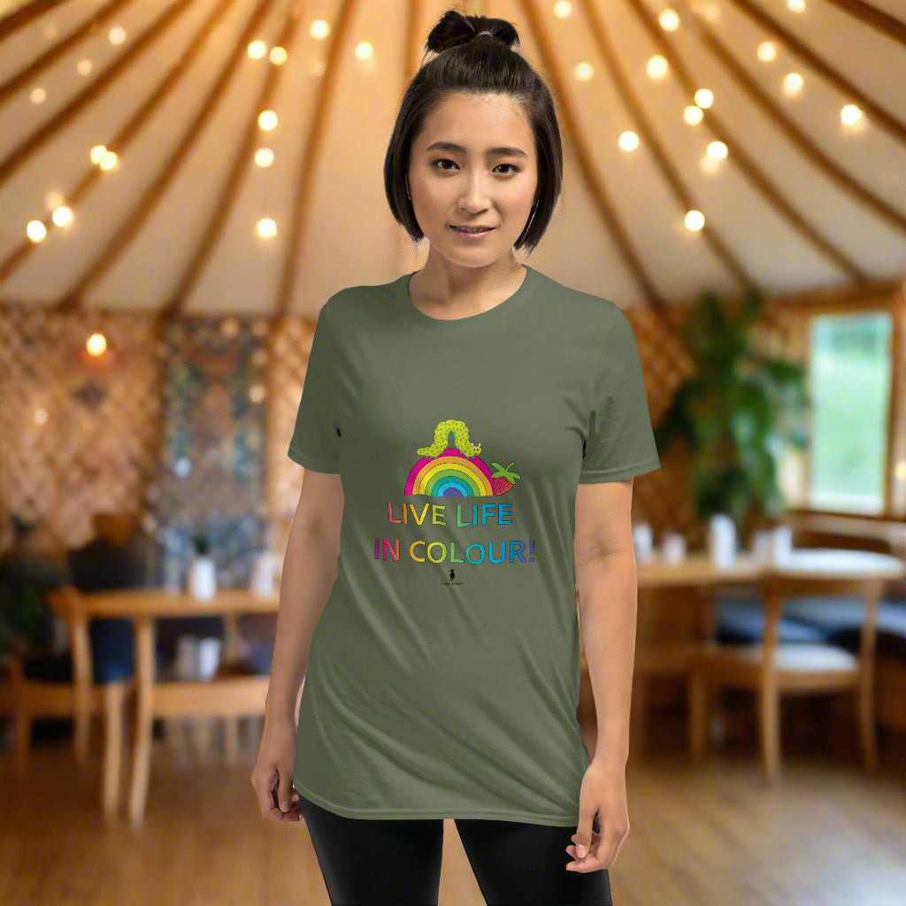 Woman wearing a khaki green 100% cotton vibrant, rainbow live life in colour t-shirt in a bohemian yurt interior decorated with fairy lights and plants.