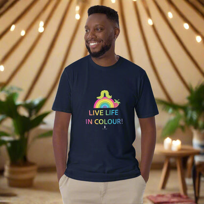 Man wearing a navy blue 100% cotton vibrant, rainbow live life in colour t-shirt in a bohemian yurt interior decorated with fairy lights, rugs, candles and plants.