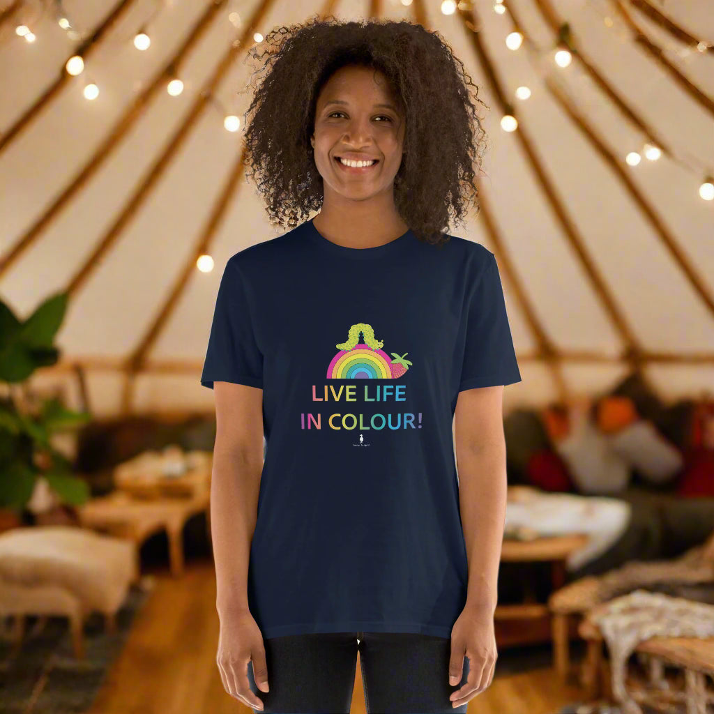 Woman wearing a navy blue 100% cotton vibrant, rainbow live life in colour t-shirt in a bohemian yurt interior decorated with fairy lights, rugs, candles and plants.