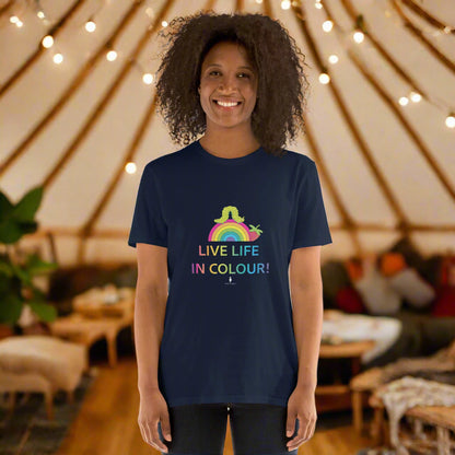 Woman wearing a navy blue 100% cotton vibrant, rainbow live life in colour t-shirt in a bohemian yurt interior decorated with fairy lights, rugs, candles and plants.