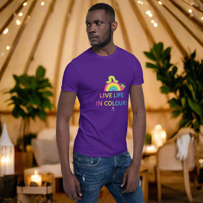 Man wearing a purple 100% cotton vibrant, rainbow live life in colour t-shirt in a bohemian yurt interior decorated with fairy lights, rugs, candles and plants.