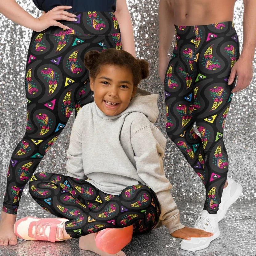 Man, woman and child wearing matching festival leggings designed in Wales - bold Black Paisley Party pattern. Silver sequin background | Sassy Seagull