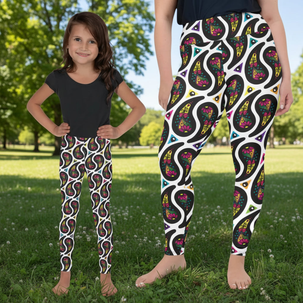 Woman and child wearing matching festival leggings designed in Wales - bold White Paisley Party pattern. Silver sequin background | Sassy Seagull