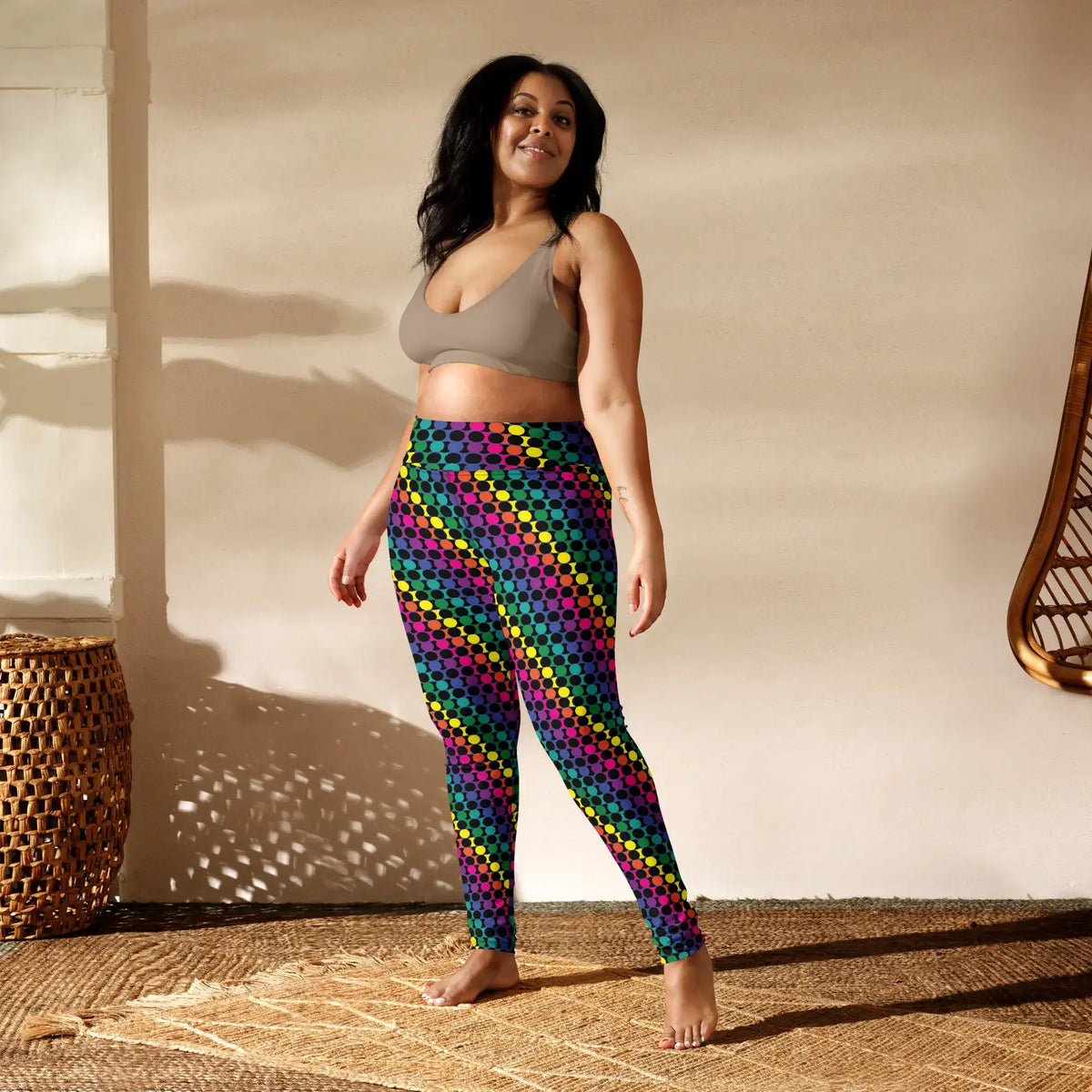 Plus size women's high waist Rainbow Geometric yoga festival leggings front view. Woman is standing in a boho yoga studio.  The Disco Lights design is a bold colourful rainbow spotty pattern. Designed in Wales, UK | Sassy Seagull. 