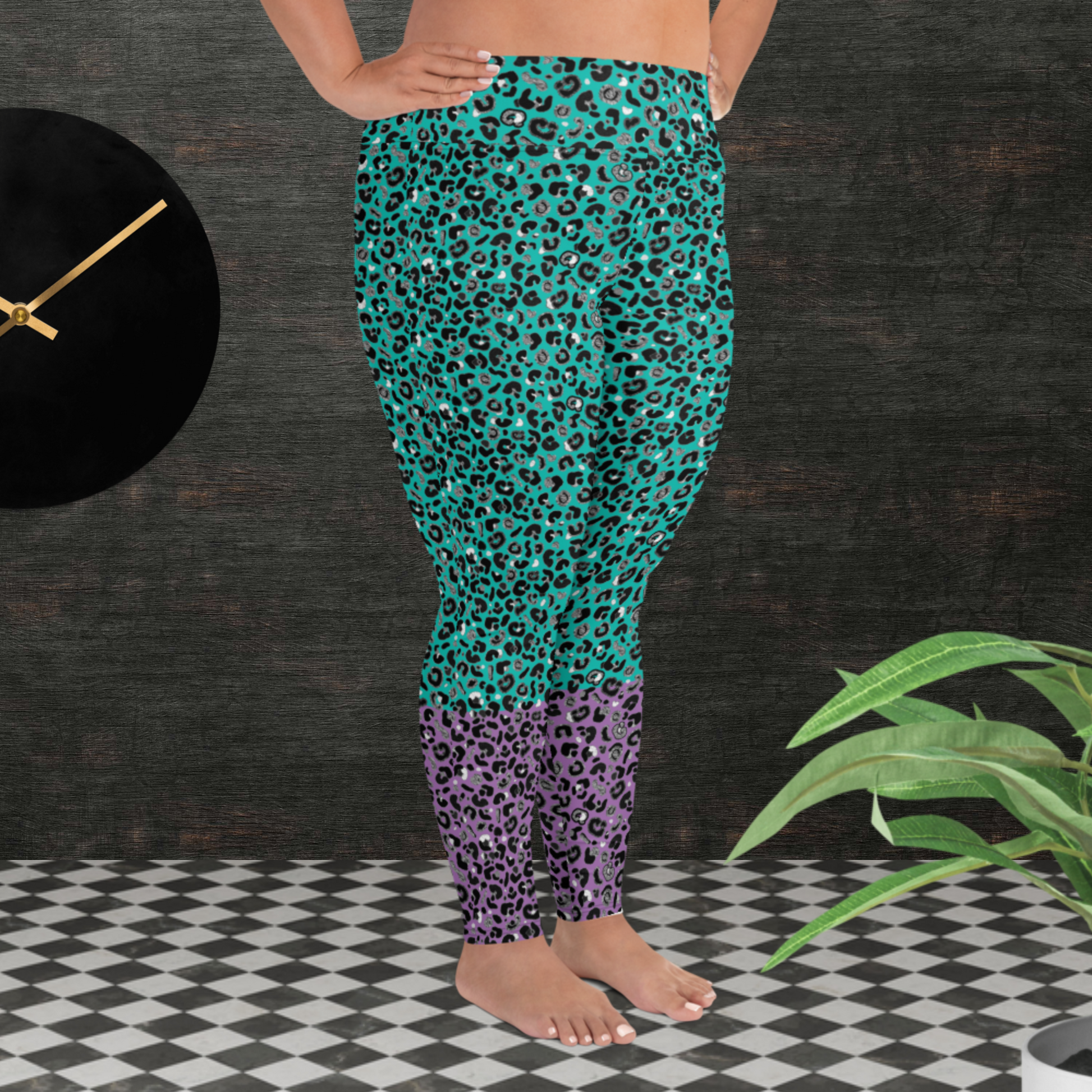 A curvy woman from the waist down wearing plus-size high-waist Purple and Green Leopard Glamour funky festival yoga leggings standing facing to the right. The woman is standing in front of a textured grey background with a black and gold wall clock to the left and a partially visible leafy plant on the floor in the bottom right.  This design features an animal print pattern in black, grey and white, printed at a medium scale. The top 3/4 background is mint green with the bottom 1/4 purple