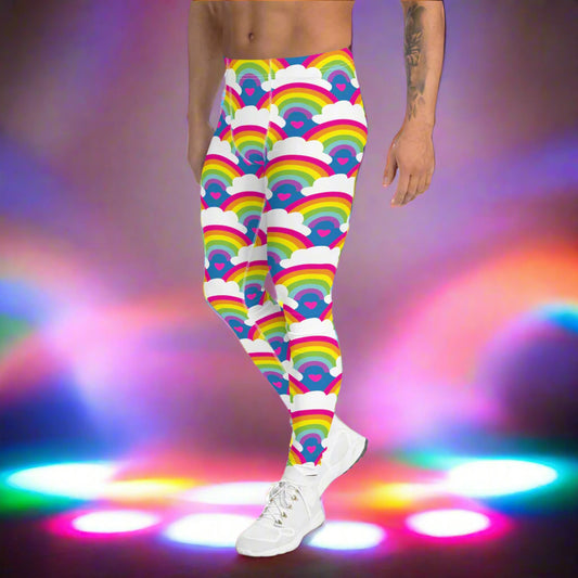 Man from the waist down wearing men's Rainbow Love funky festival yoga leggings standing facing to the left with his hands by his sides. The man is standing on a dance floor with colourful stage light spots on the floor. The background is hazy mixed with glow from the coloured lights. The rainbow love pattern features repeating rainbows and white fluffy clouds with a small pink heart beneath each rainbow. The background colour is royal sky blue