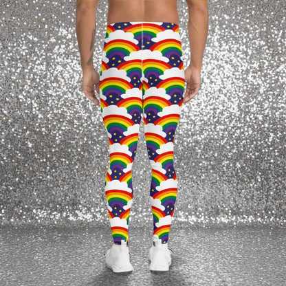 Man from the waist down wearing men's Rainbow Sparkle funky festival yoga leggings standing facing away with his hands by his sides. The man is standing in a nightclub with a colourful pink lighting glow and other club goers in the background. The rainbow sparkle pattern features repeating rainbows and white fluffy clouds with three small yellow stars beneath each rainbow. The background colour is navy blue