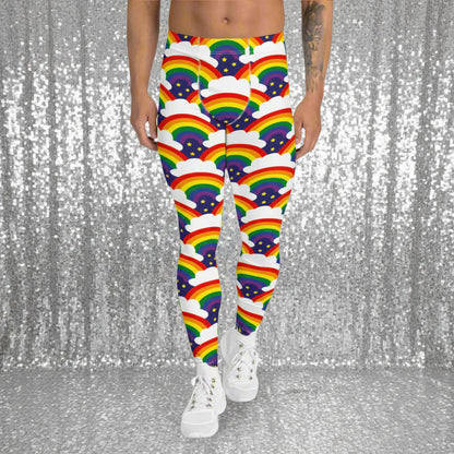 Man from the waist down wearing men's Rainbow Sparkle funky festival yoga leggings standing facing forwards with his hands by his sides. The man is standing on a dance floor with colourful pink stage light spots around him. The background is hazy mixed with a pink glow from the coloured lights. The rainbow sparkle pattern features repeating rainbows and white fluffy clouds with three small yellow stars beneath each rainbow. The background colour is navy blue