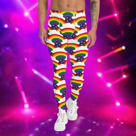 Man from the waist down wearing men's Rainbow Sparkle funky festival yoga leggings standing facing forwards with his hands by his sides. The man is standing on a dance floor with colourful pink stage light spots around him. The background is hazy mixed with a pink glow from the coloured lights. The rainbow sparkle pattern features repeating rainbows and white fluffy clouds with three small yellow stars beneath each rainbow. The background colour is navy blue