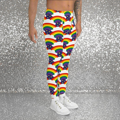 Man from the waist down wearing men's Rainbow Sparkle funky festival yoga leggings standing facing  to the right with his hands by his sides. The man is standing in a nightclub with colourful pink and purple lighting in the background. The rainbow sparkle pattern features repeating rainbows and white fluffy clouds with three small yellow stars beneath each rainbow. The background colour is navy blue