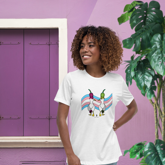 Woman standing facing forwards and looking to the left, wearing a fitted white Sassy Seagull Trans flag LGBTQ+ Pride T-Shirt and pale stonewash blue jeans.She is standing against a purple and white background with a tall green leafy plant to the front right.The t-shirt is white with short sleeves. The graphic shows two cartoon style seagulls wearing colourful hats walking away in front of a trans pride flag. It is a soft playful design for everyday wear