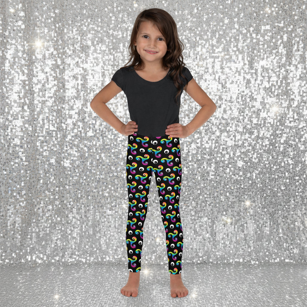 Young girl standing facing forward wearing a black t-shirt and trippy triskelion leggings with a disco dance floor background