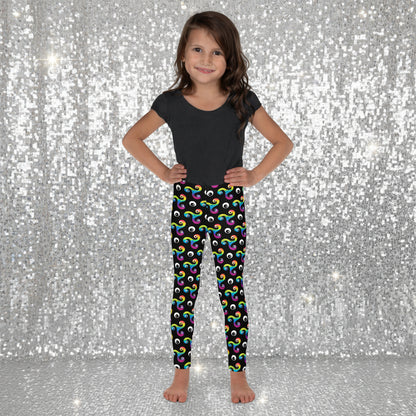 Young girl standing facing forward wearing a black t-shirt and trippy triskelion leggings with a disco dance floor background