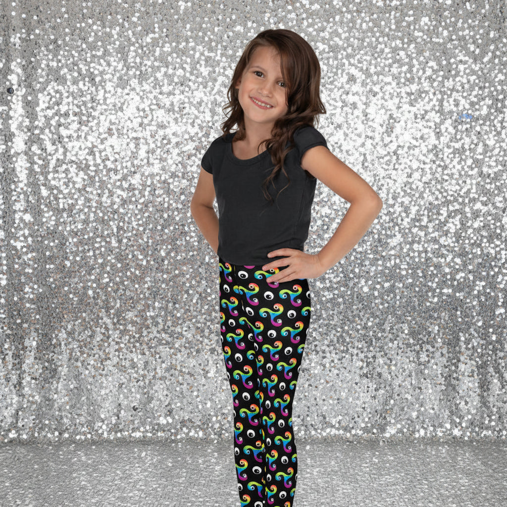 Young girl standing facing to the left wearing a black t-shirt and trippy triskelion leggings with a disco lights background