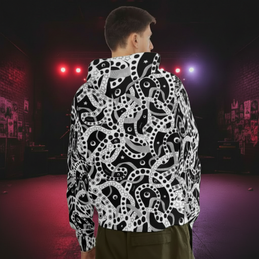 Man from the chin down to the waist, posing standing facing away wearing a 100% cotton bold black and white Who's Afraid Of The Dark all-over print hoodie. He is standing in a park with trees in the background. The hoodie has an abstract design made up of interwoven shapes detailed with spots, stars and lines. It is a unique and bold design for everyday wear.