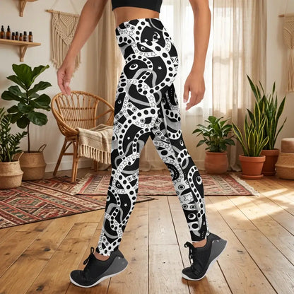 Women's high waist black and white yoga festival leggings lifestyle side view. Woman is standing in a boho yoga studio.  The Who's Afraid Of The Dark design is a bold abstract pattern. Designed in Wales, UK | Sassy Seagull. 