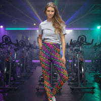 High waist Fire Tribal Frog festival yoga leggings lifestyle. Woman is standing in an outdoor setting.  The Tribal Frog design is a bold colourful abstract print on a blended pink, purple and orange background. Designed in Wales, UK | Sassy Seagull. 