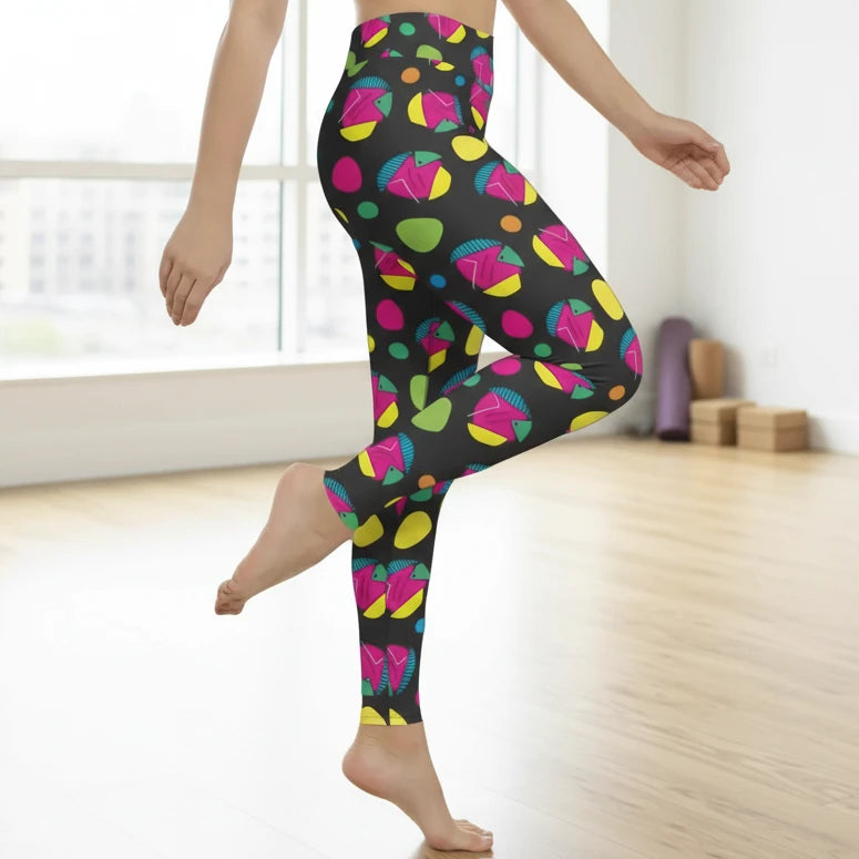 High waist Funk Party Original festival yoga leggings side view. The woman is standing in a rustic boho setting with plants, fairy lights and bunting in the background.  The Funk Party design is a bold colourful abstract print. Designed in Wales, UK | Sassy Seagull. 