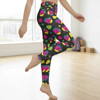 High waist Funk Party Original festival yoga leggings side view. The woman is standing in a rustic boho setting with plants, fairy lights and bunting in the background.  The Funk Party design is a bold colourful abstract print. Designed in Wales, UK | Sassy Seagull. 