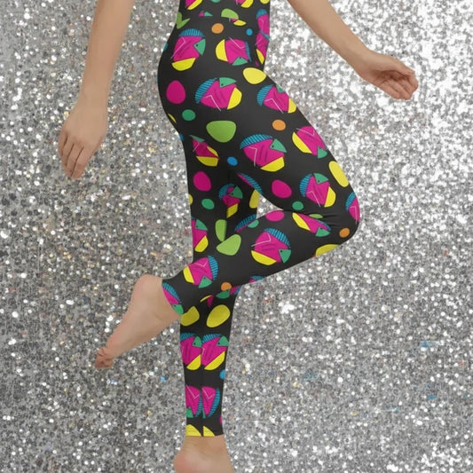 High waist Funk Party Original festival yoga leggings side view. The woman is standing in a rustic boho setting with plants, fairy lights and bunting in the background.  The Funk Party design is a bold colourful abstract print. Designed in Wales, UK | Sassy Seagull. 